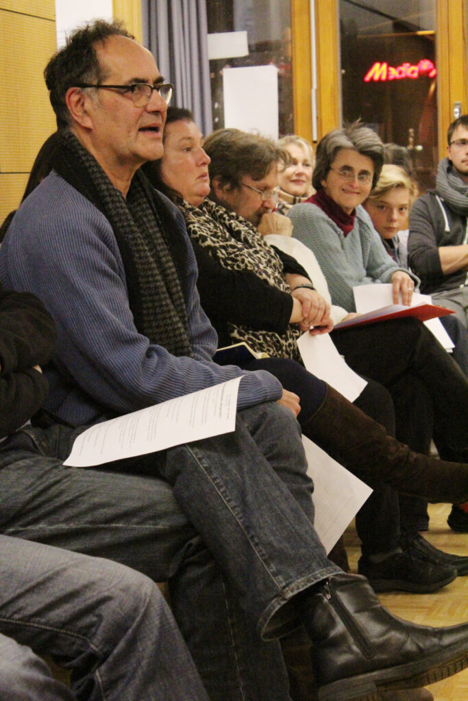 Eine Gruppe von Personen, die an einer Diskussionsrunde teilnehmen, mit Notizen in der Hand.