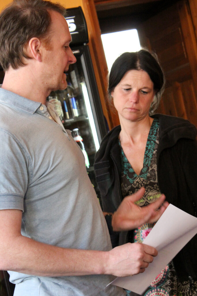 Mann und Frau im Gespräch, der Mann hält ein Blatt Papier in der Hand.